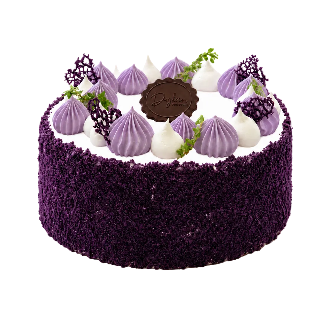 A round ube cake with a dark purple crumb-coated exterior, white frosting base, and purple meringue-like piped decorations around the top, plus a central chocolate plaque and small green leaf accents, photographed on a plain white background.